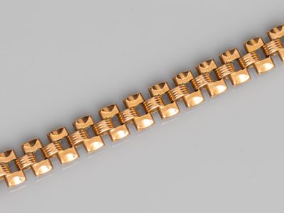 gros plan d'un bracelet en or sur une surface grise