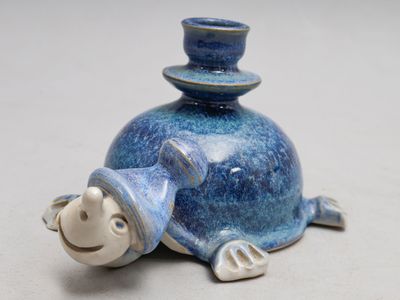 une figurine en céramique représentant une tortue coiffée d'un haut-de-forme