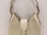 a white purse with a tan handle on a white surface