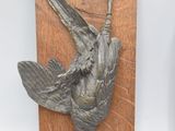 two sculptures of birds that are on a wooden plaque