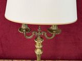 a brass table lamp with a white shade on top of it