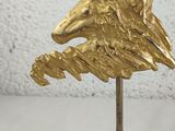brass eagle head on a black marble base on a white background