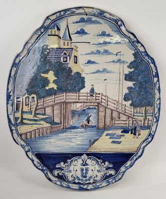 assiette bleue et blanche ornée d'une peinture représentant un pont enjambant une rivière