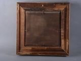 an old wooden frame with a mirror hanging on the wall