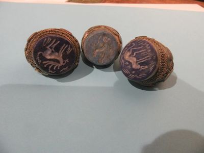trois bagues ornées de motifs, exposées sur une table