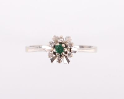 gros plan d'une bague avec une pierre verte entourée de diamants