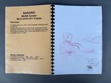 an open notebook with a drawing of a woman sitting on a bench
