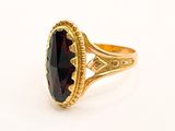 a close up of a gold ring with a large garnet stone