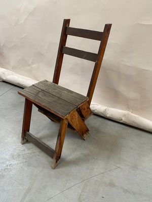 a wooden chair sitting in front of a white wall