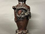 a bronze vase with a dragon on it on a table