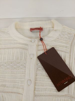 un cardigan blanc muni d'une étiquette et auquel est attachée une étiquette