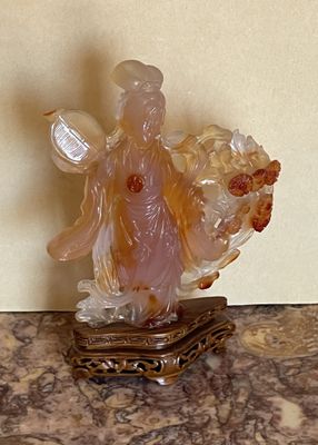 une figurine représentant une femme tenant un panier de fleurs posé sur une table