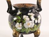 a black vase with white flowers on it on a stand