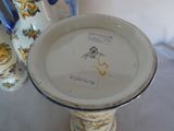 a white vase with a blue handle and a white plate with a picture of a horse on it