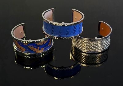 trois bracelets de couleurs différentes sur un fond noir avec des reflets