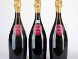 trois bouteilles de champagne posées les unes à côté des autres sur une surface blanche