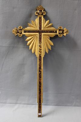 une croix en or richement décorée, surmontée d'un soleil rayonnant