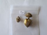 une broche en or et une paire de boucles d'oreilles posées sur une surface blanche