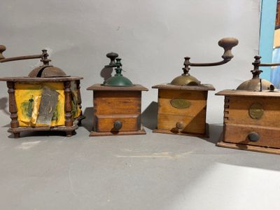 three old fashioned coffee grinders are lined up on a table