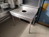 une table en acier inoxydable sur laquelle est posé un faitout, dans une cuisine