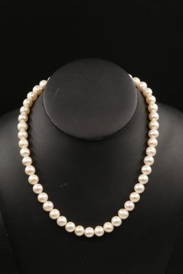 a white pearl necklace on a black mannequin