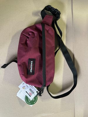 a red bag with a tag on it sitting on the floor