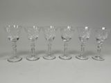 six crystal wine glasses lined up in a row on a table
