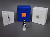 une petite figurine représentant un homme en uniforme, à côté d'une boîte