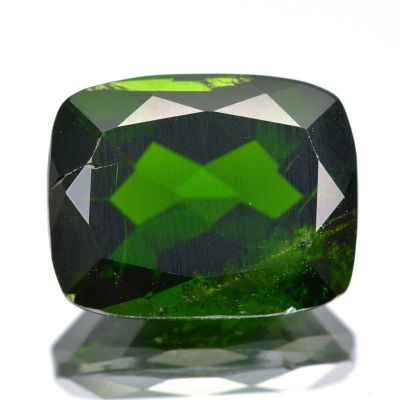 a close up of a green tourmaline gemstone on a white surface