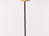 une lampe noire et dorée posée sur un pied noir, sur fond blanc