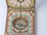 an old wooden compass with a needle in it on a white surface