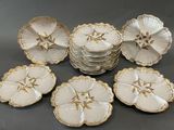 six assiettes blanches et dorées ornées de fleurs, posées sur une table
