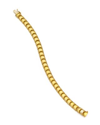 gros plan d'un bracelet en or sur fond blanc