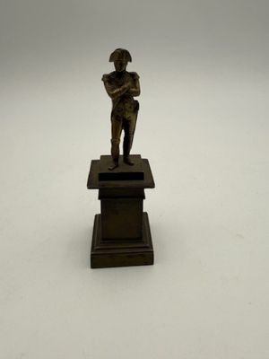 figurine en bronze représentant un garçon tenant un livre, posée sur un socle