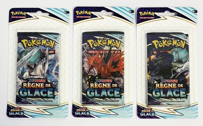 On voit trois paquets de cartes à collectionner Pokémon posés sur une surface blanche.