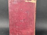 an old red book sitting on top of a black surface