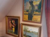 paintings on the wall above a bed in a room