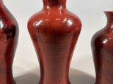 three red vases sitting next to each other on a white surface