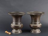 deux vases en métal posés l'un à côté de l'autre sur une table