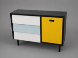 a black, white and yellow chest of drawers against a gray background