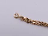 a close up of a gold chain bracelet on a white surface