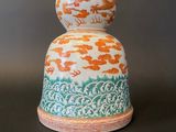 an orange and white vase sitting on top of a black table