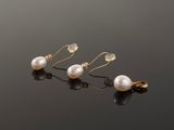 a pair of pearl and gold earrings on a black surface