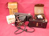 three old cameras and a case on a pink background