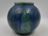 un vase bleu et vert posé sur une surface blanche