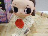 a small figurine of a girl holding a red wax stamp