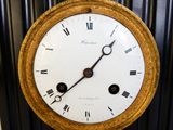 a gold clock with roman numerals on the face