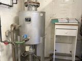 a water heater in the corner of a room next to a desk