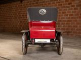 a red and black antique car parked in front of a brick wall