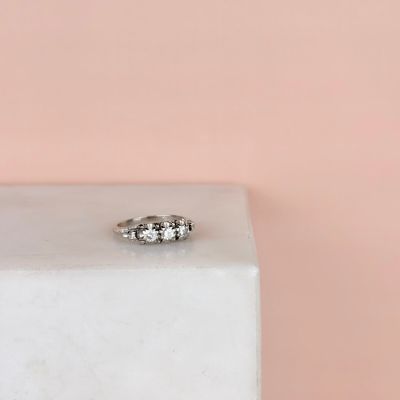 un gros plan d'une bague en diamant posée sur un bloc blanc